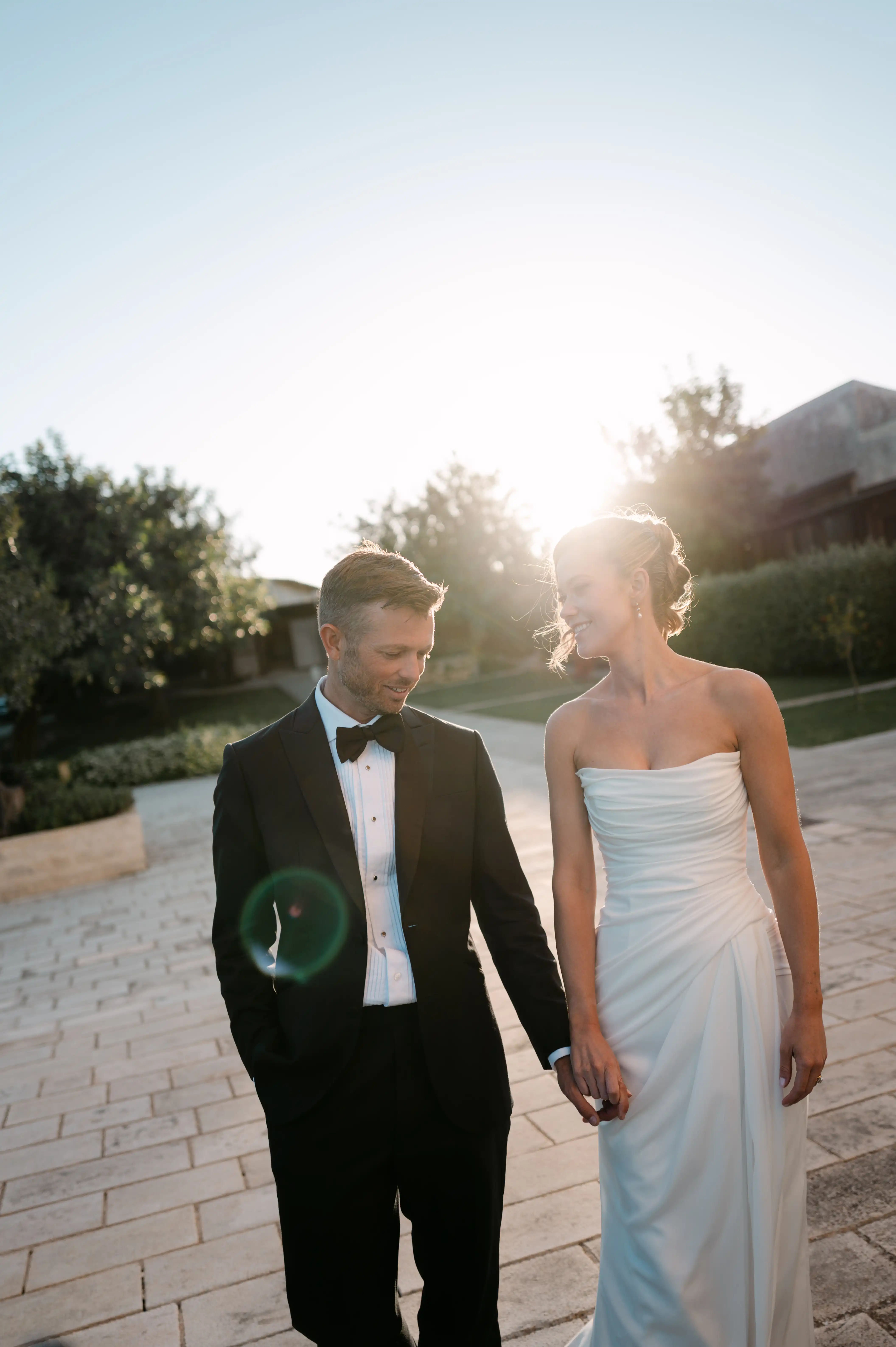Elegant newlywed couple holding hands during sunset portraits at a luxury destination wedding in Sicily